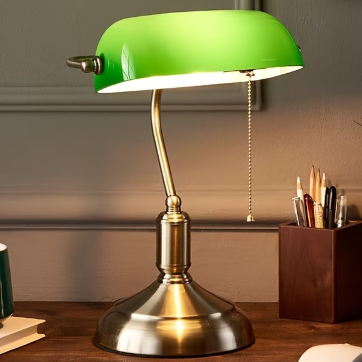 Green bankers lamp with brass base on a wooden surface in an office. 